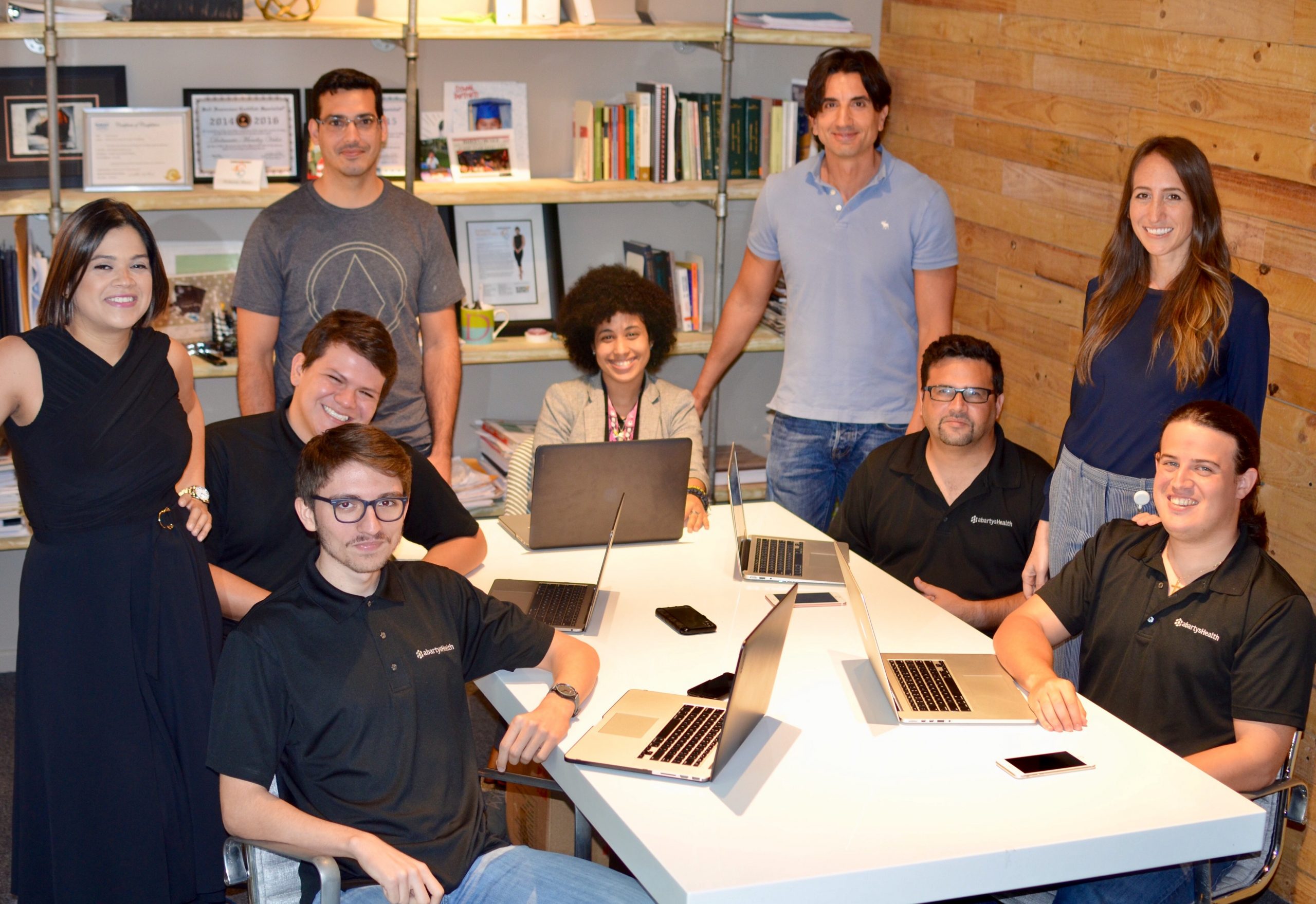 abartys health team members sitting around a table with their laptops smiling for a photo